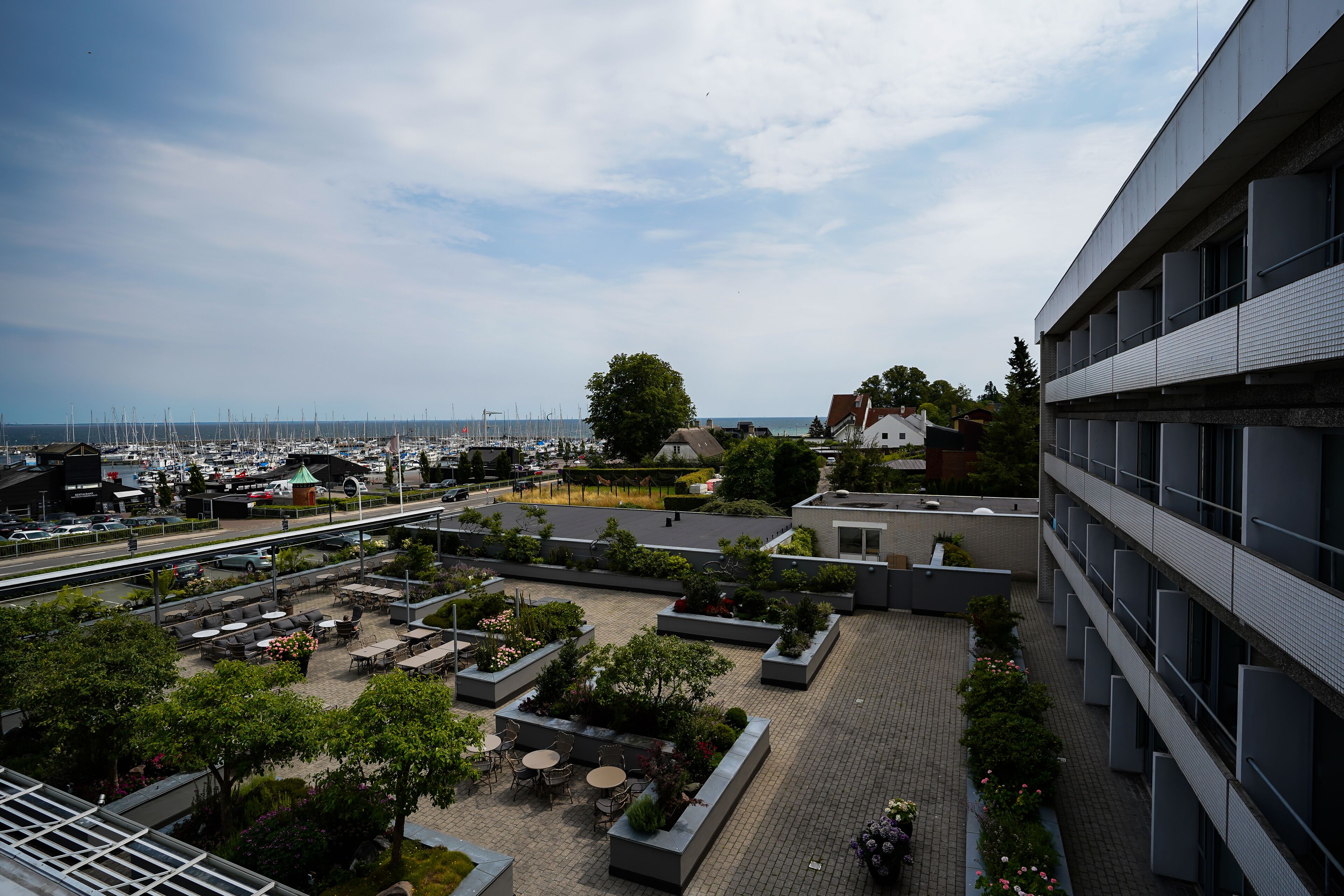 A rooftop terrace with outdoor seating, a view of the marina, and a modern building with balconies.