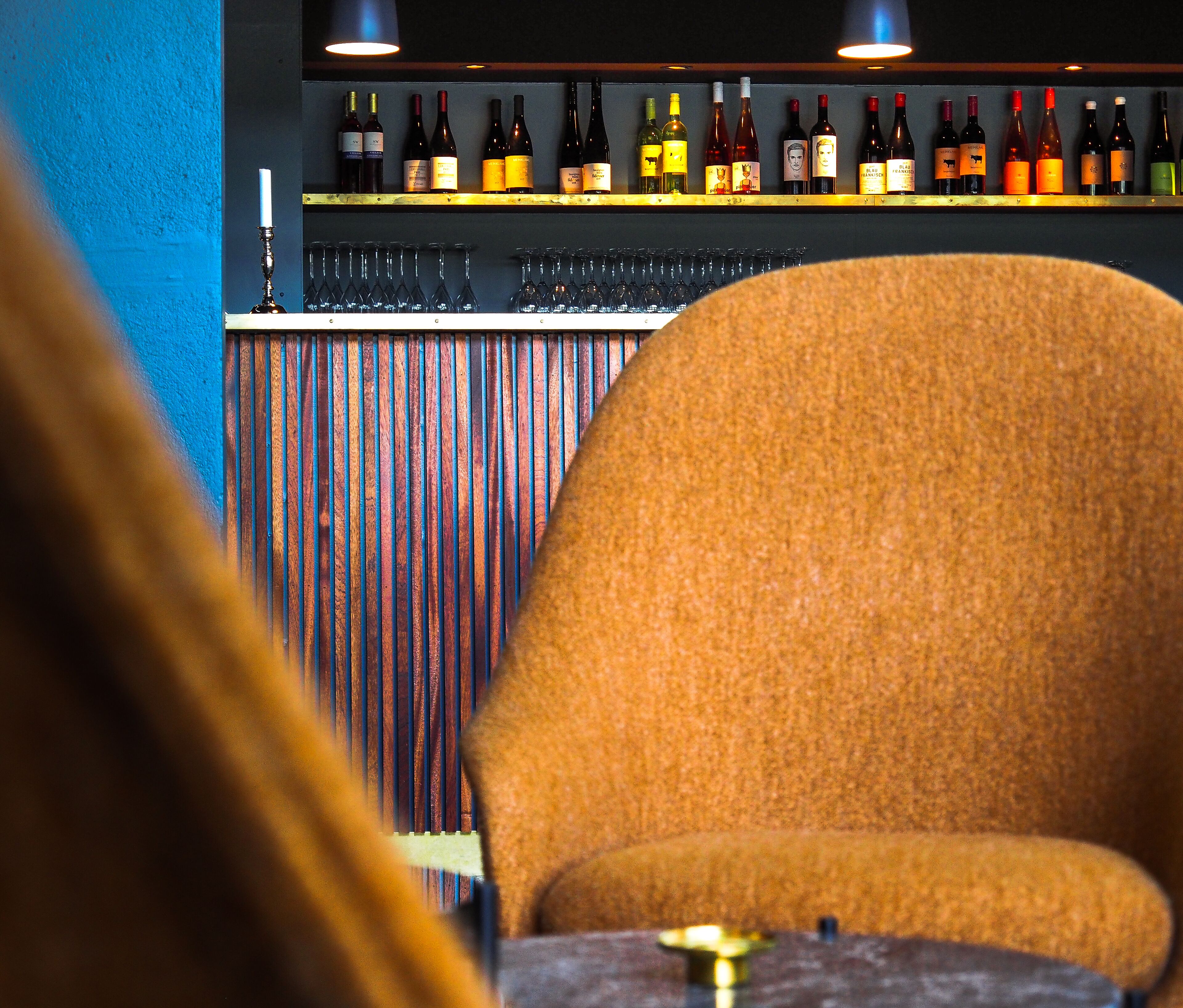 A bar area with a variety of wine bottles and glasses on shelves.