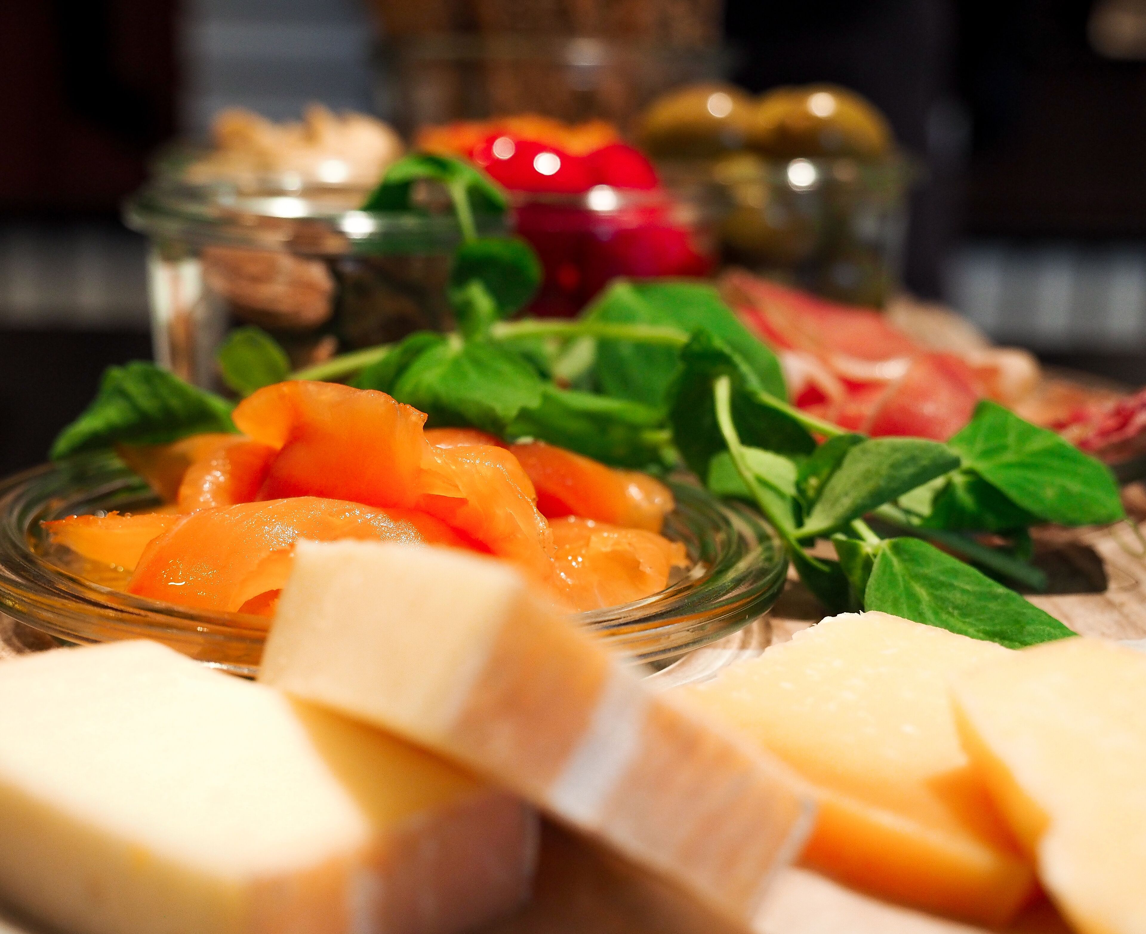 A variety of cheeses and pickled vegetables on a wooden table.