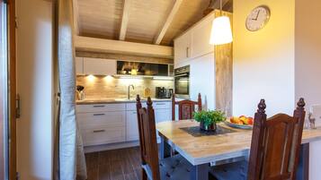 Una cucina moderna con mobili bianchi, un tavolo da pranzo in legno e una sveglia appesa al muro.