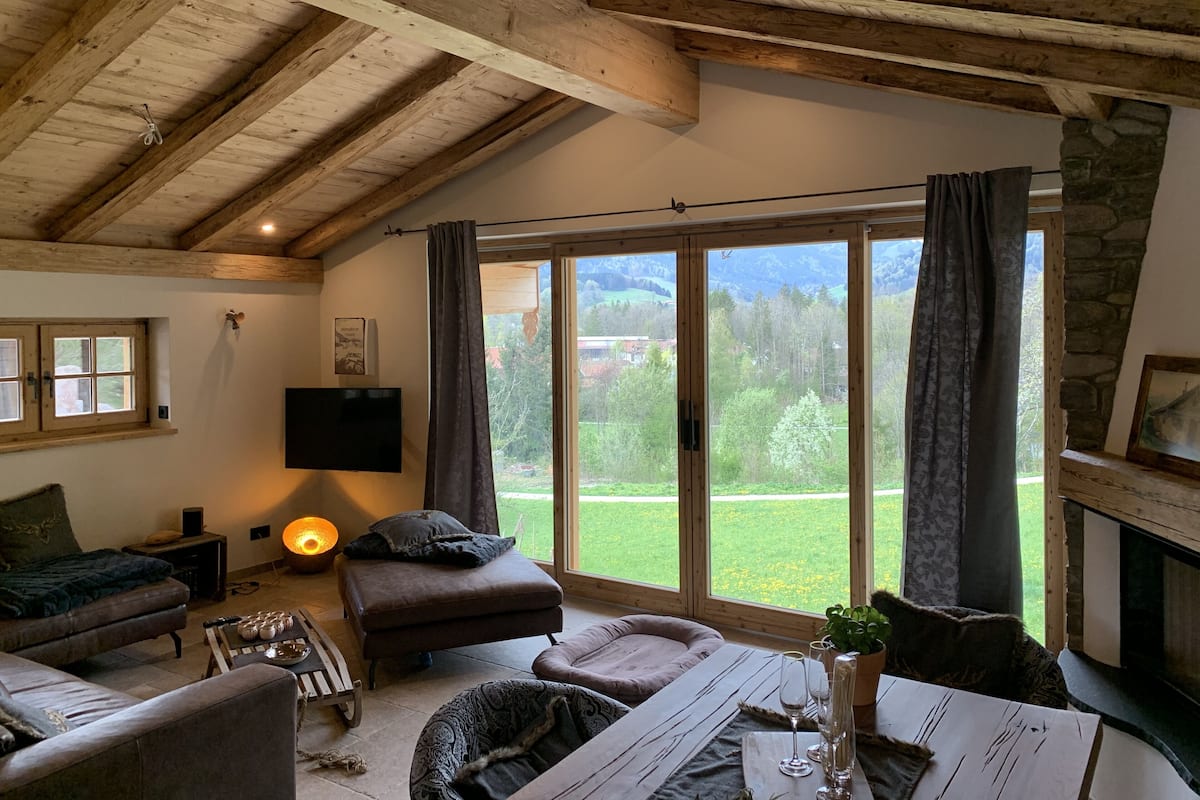 Una sala de estar acogedora con chimenea, un ventanal con cortinas, un televisor de pantalla plana y una zona de estar cómoda.