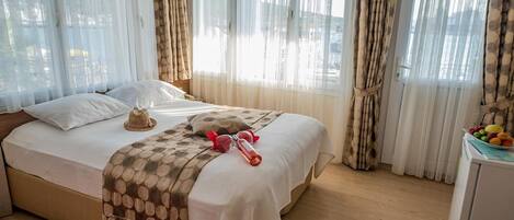 A neatly made bed with a patterned blanket, pillows, and a small hat on the headboard.