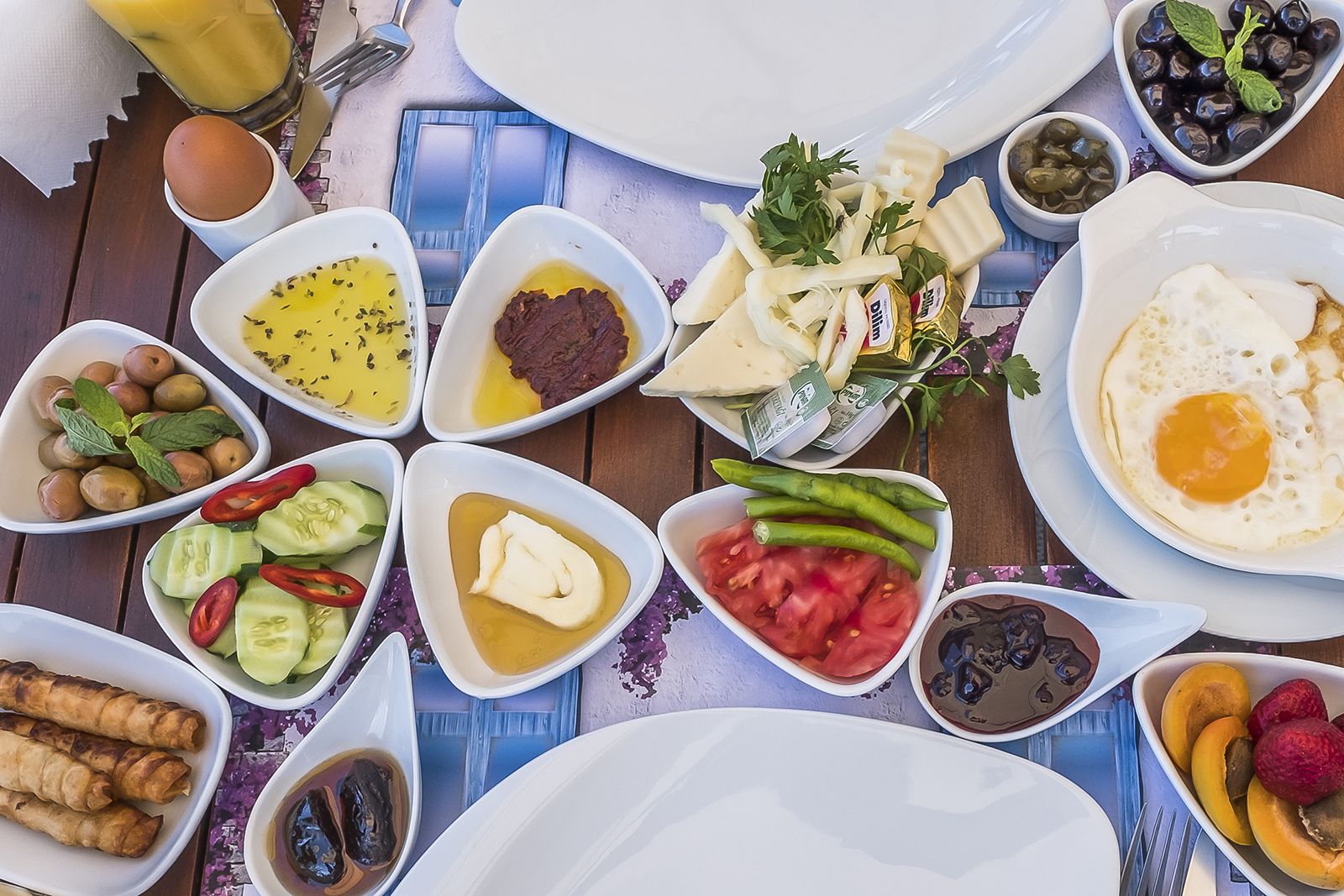 A table with various breakfast dishes including eggs, vegetables, and condiments.