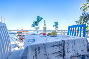 A table set with a bottle, glasses, and fruit, overlooking a marina with boats. - Villa Vongole (Cesme)