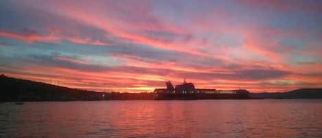 A sunset over a body of water with a large building silhouetted against the sky.
