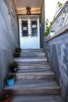 Un conjunto de escalones de mármol que conducen a una puerta blanca con paneles de vidrio decorativos.