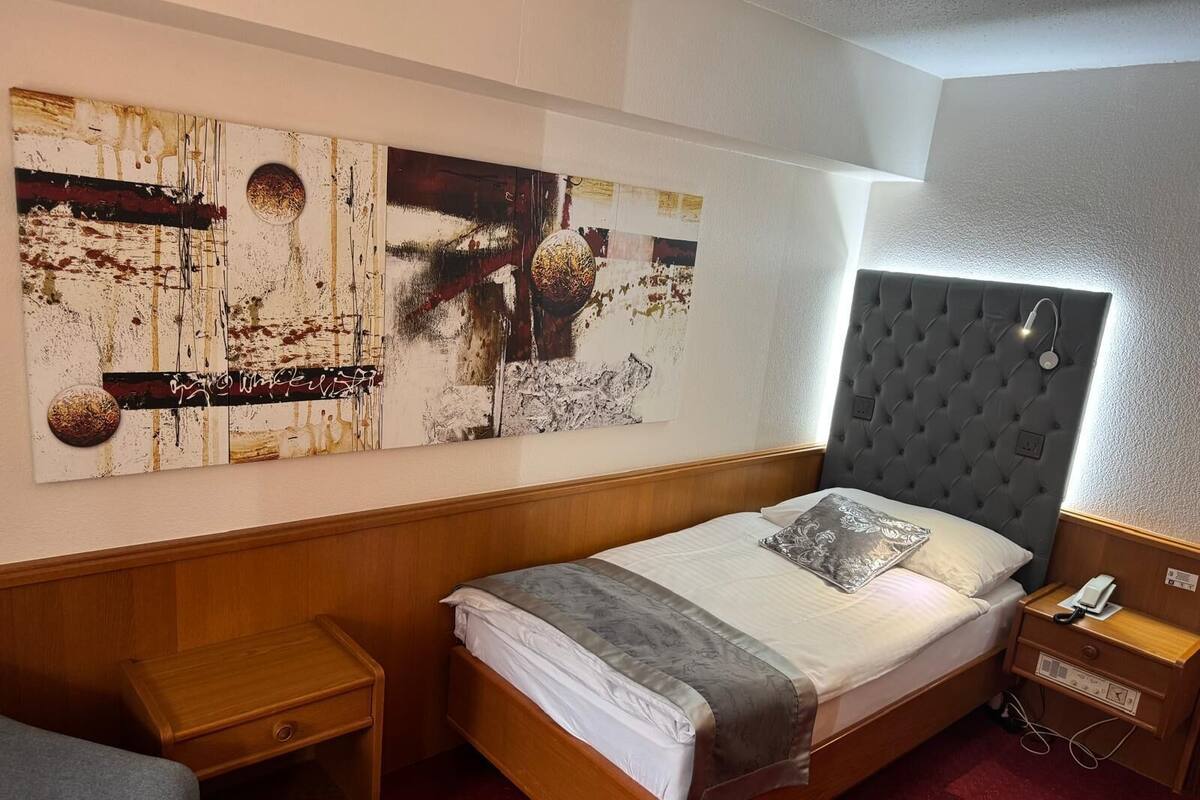 A neatly arranged hotel room with a bed, bedside table, and a wall-mounted artwork.
