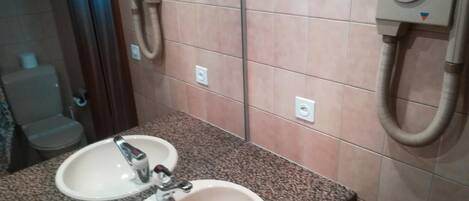 A bathroom with two sinks, a mirror, and a toilet.