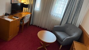 A hotel room with a desk, chair, and a small round table. - Hôtel des Trois Rois (Le Locle)