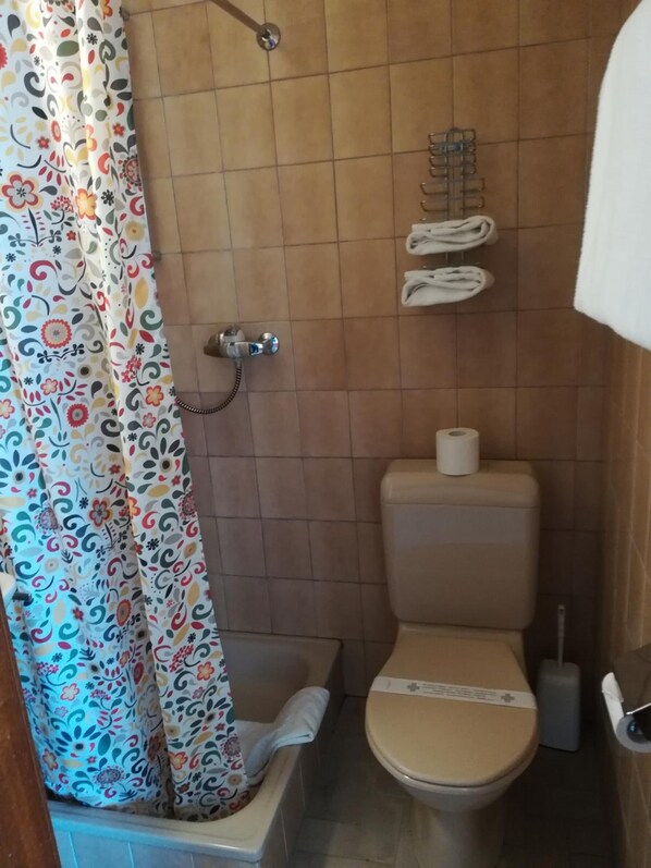 A small bathroom with a shower, toilet, and a towel rack.