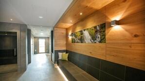A modern hallway with a wooden accent wall, a bench, and a wall-mounted picture of a waterfall.