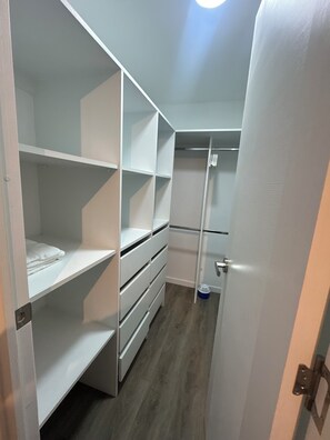 A walk-in closet with open shelving, a hanging rod, and a door with a handle.
