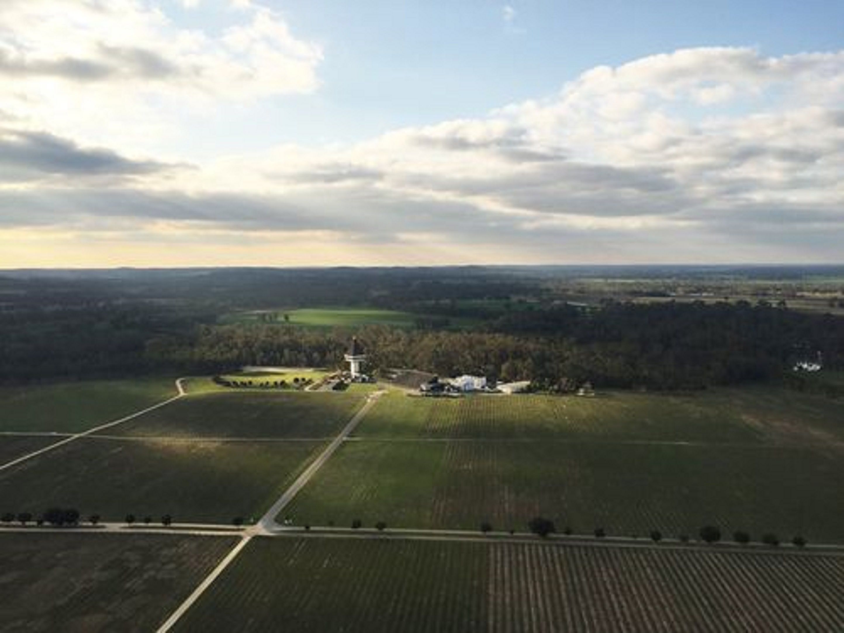 Vista aérea de un paisaje rural con campos, una casa de campo y una torre.