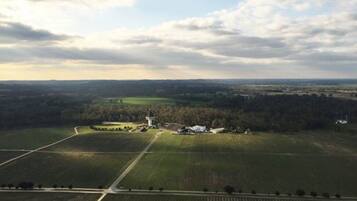Vista aérea de un paisaje rural con campos, una casa de campo y una torre.