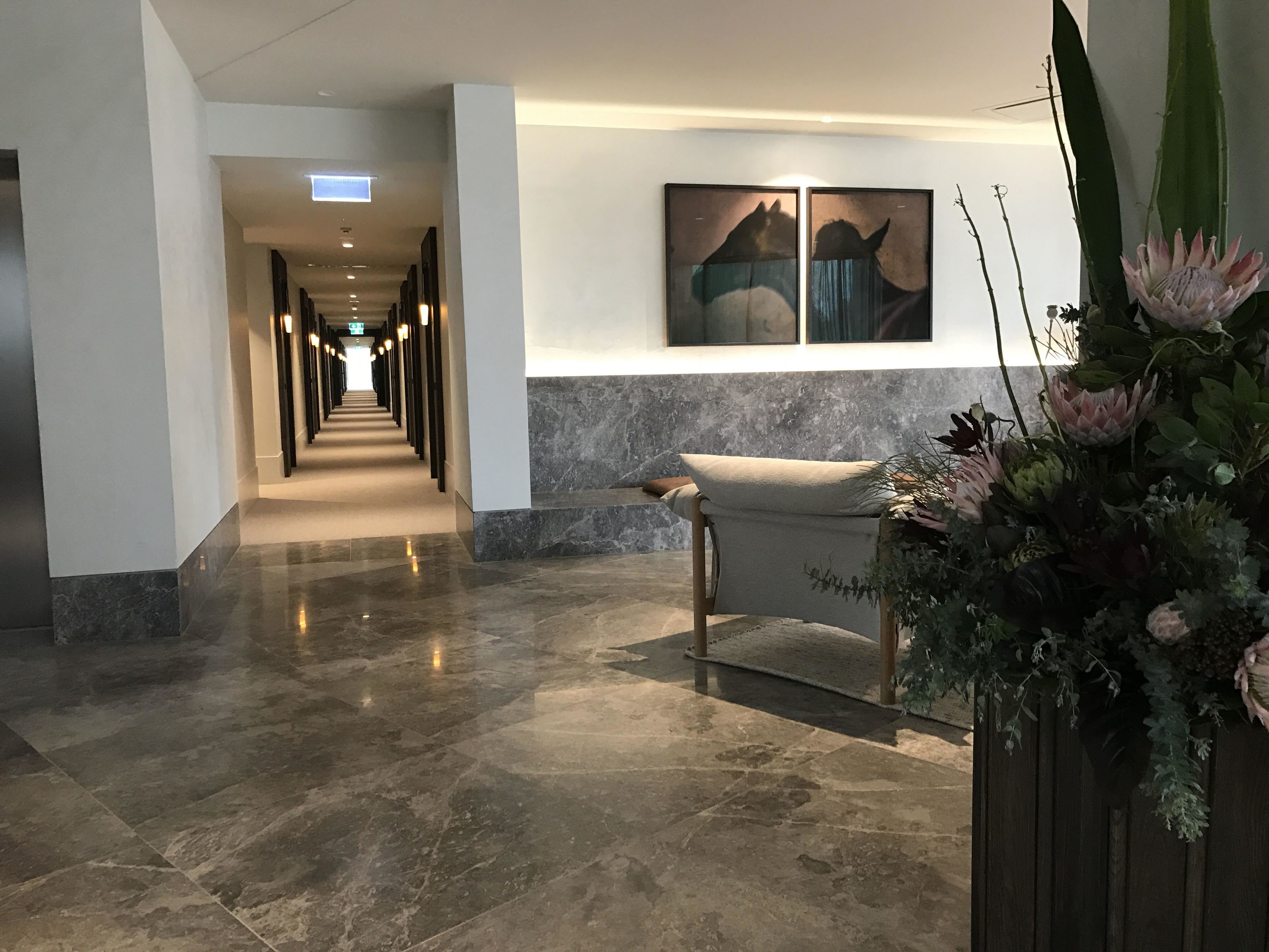 Un vestíbulo de hotel con piso de mármol, un mostrador de recepción y una obra de arte colgada en la pared.