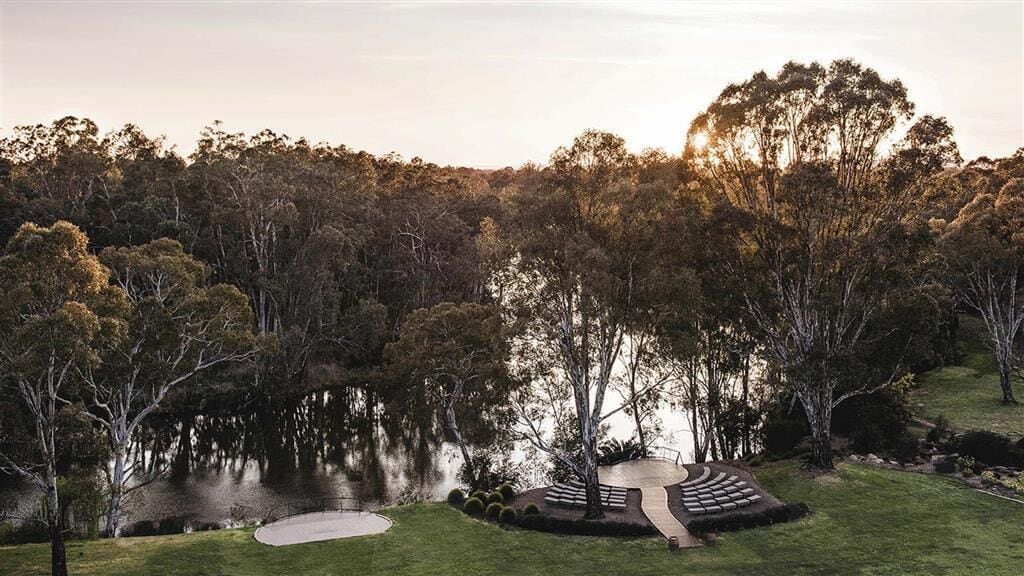 A serene landscape with a pond, trees, and a circular stone pathway.