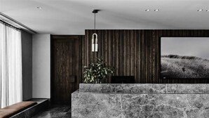 Un intérieur moderne avec un comptoir d’accueil en marbre, un mur recouvert de panneaux en bois et une grande œuvre d’art encadrée.