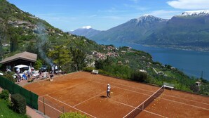 Una cancha de tenis con red, rodeada de vegetación y un paisaje montañoso.