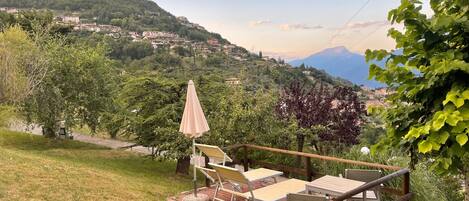 A patio with outdoor furniture, a tree, and a view of a hillside village.