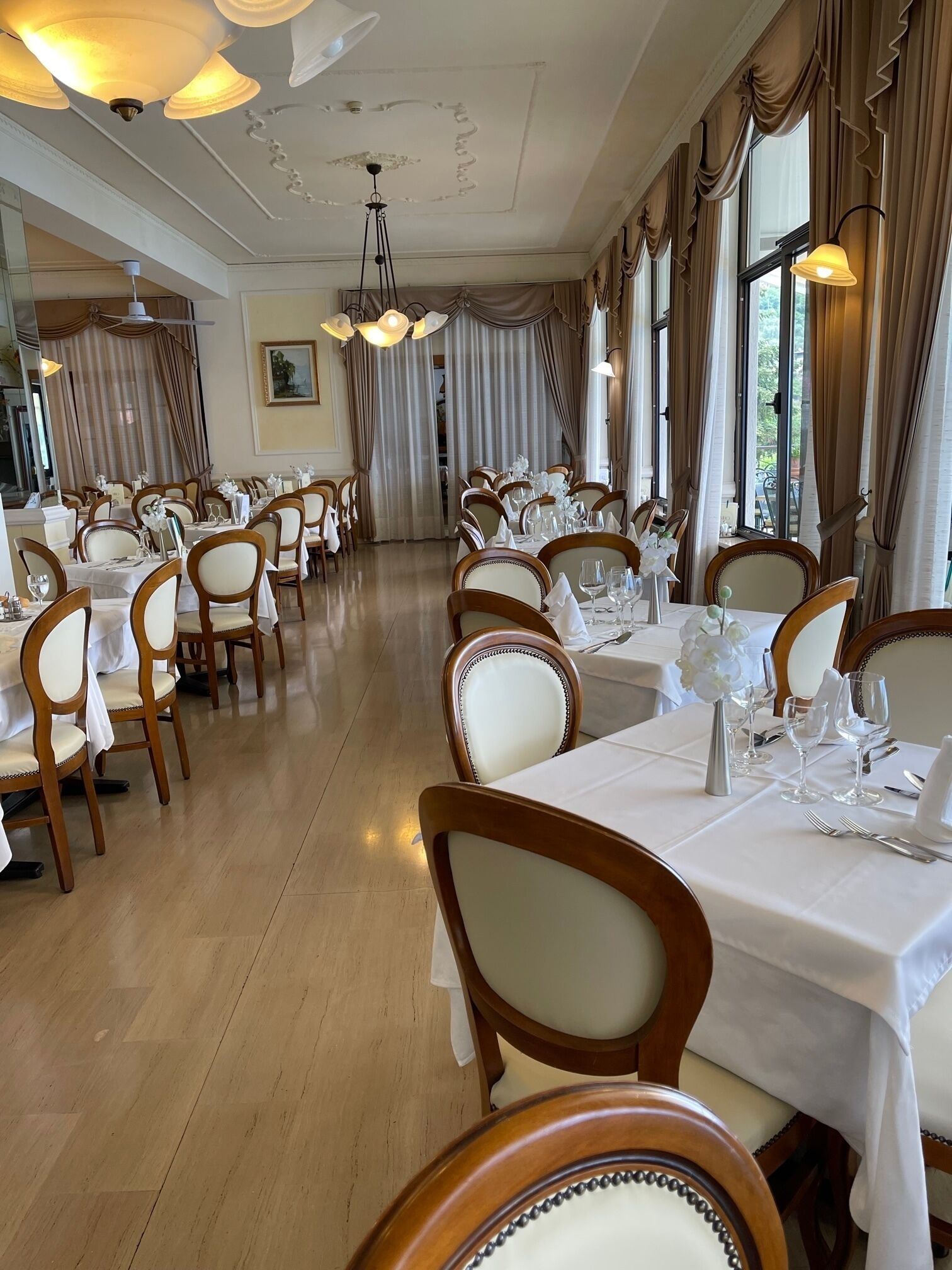 A dining area with multiple tables, chairs, and chandeliers.