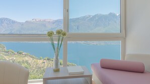 Una habitación con un amplio ventanal que ofrece vistas a montañas y una masa de agua.