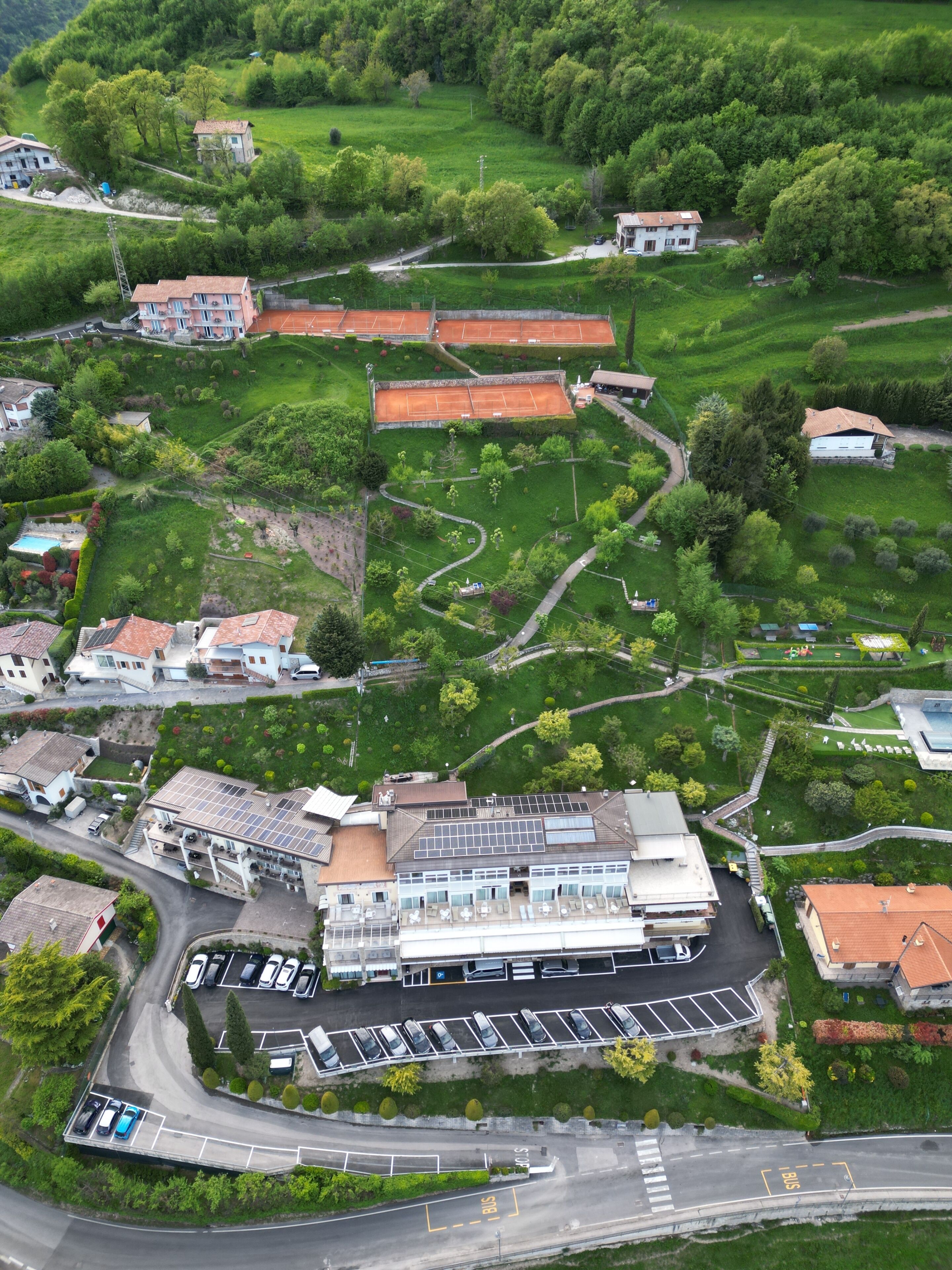 An aerial view of a residential area with houses, a parking lot, and a building with a solar panel roof.