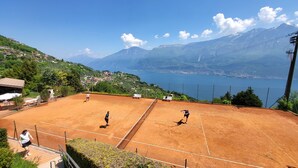 Una cancha de tenis con vistas panorámicas a una montaña y un lago.