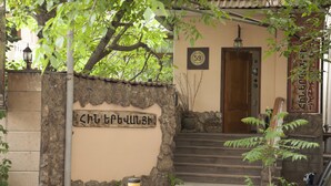 A stone wall with a sign, a wooden door, and a staircase leading to a building entrance. - Hin Yerevantsi (Yerevan)