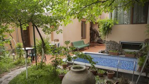 A courtyard with a pool, potted plants, a bench, and a TV. - Hin Yerevantsi (Yerevan)