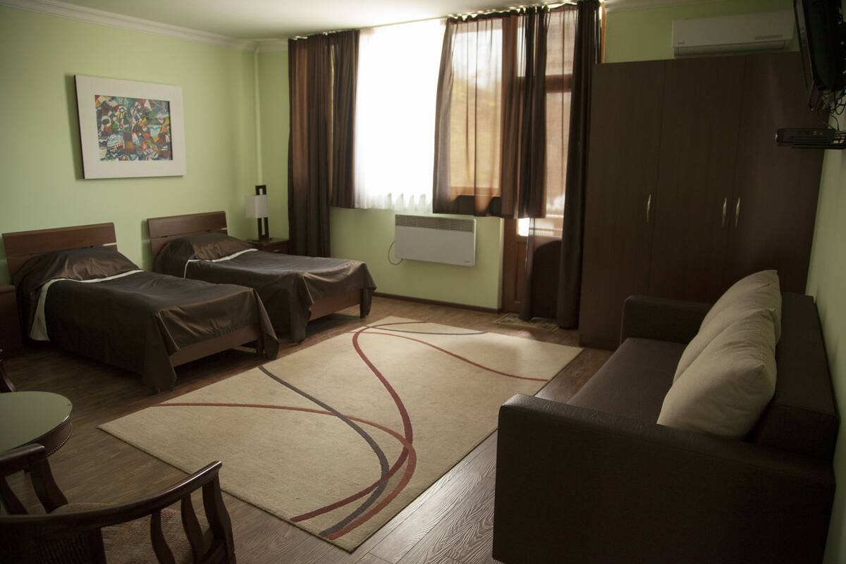 A hotel room with two beds, a sofa, a table, and a chair.
