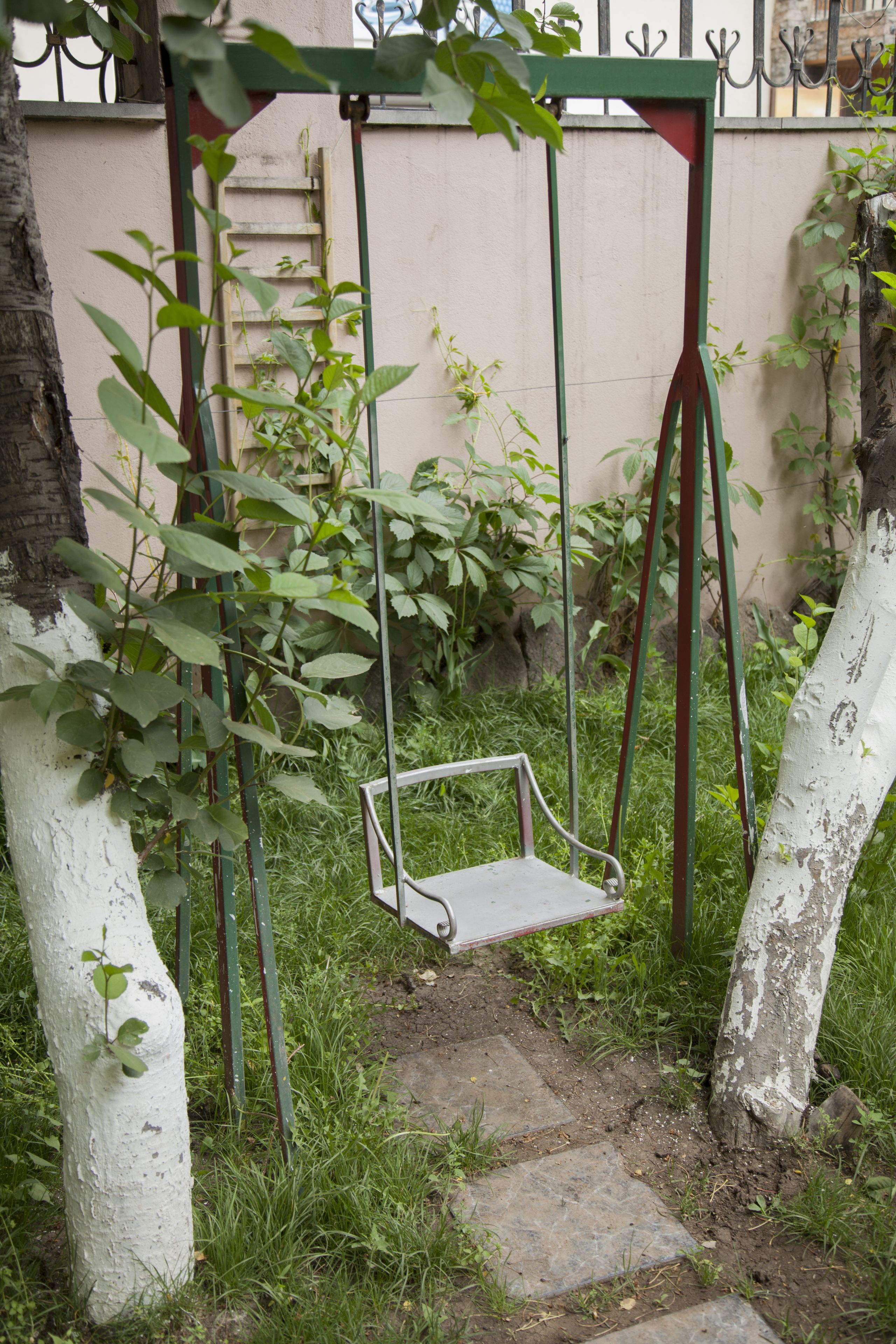 A swing set in a garden area with a stone pathway.