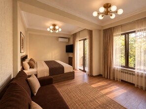 A hotel room with a bed, a sofa, a television, and a large window with curtains. - Hin Yerevantsi (Yerevan)