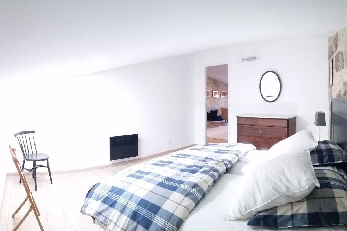 A bedroom with a bed, a chair, a dresser, and a mirror.