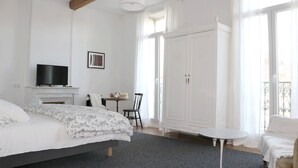 Un dormitorio con cama, televisor, chimenea, armario y balcón.