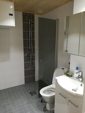 A modern bathroom with a shower, toilet, and sink.