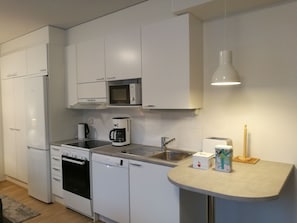 A modern kitchen with white cabinets, a microwave, a coffee maker, a dishwasher, and a sink.