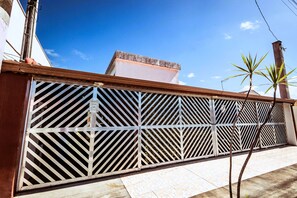 A metal fence with diagonal slats, a tiled walkway, and a clear blue sky. - Pousada Peruibe 455 (Peruíbe)