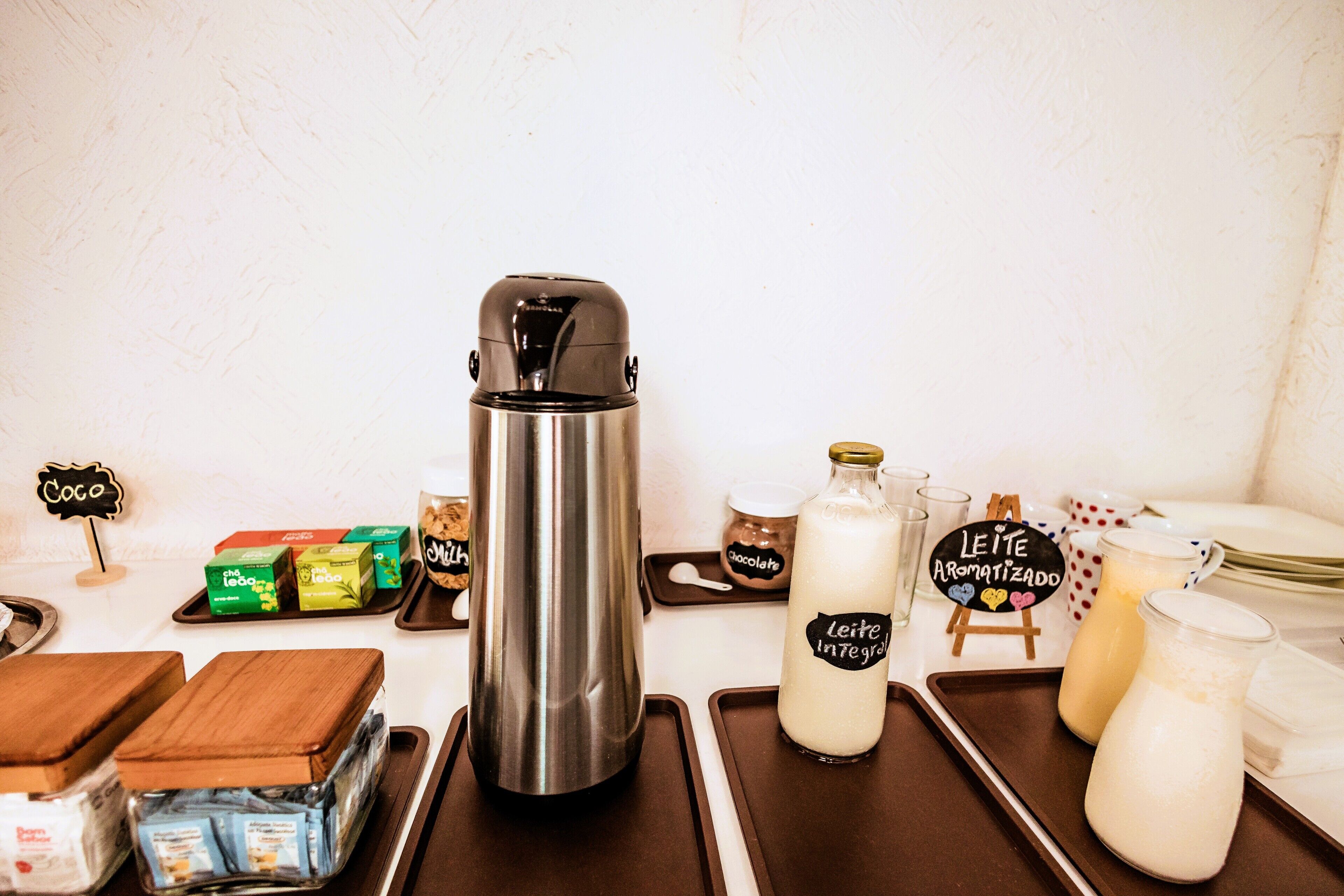 Eine Kaffeestation mit Edelstahl-Kaffeekanne, Milchflaschen und verschiedenen Kaffeekapseln.