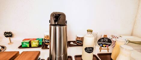 Eine Kaffeestation mit Edelstahl-Kaffeekanne, Milchflaschen und verschiedenen Kaffeekapseln.
