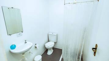 A small, clean bathroom with a sink, toilet, and a mirror.