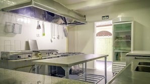 Une cuisine équipée d’une cuisinière à gaz, d’ustensiles suspendus et d’un panneau de signalisation verte indiquant la sortie.