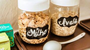 Två glasburkar med vita lock, den ena märkt med texten ”Avelho” och den andra med ”Hortelã”, och de innehåller olika typer av spannmål.