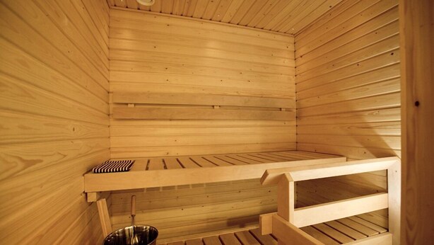 A sauna with wooden benches and a metal basin. - RovaVisit Center (Rovaniemi)