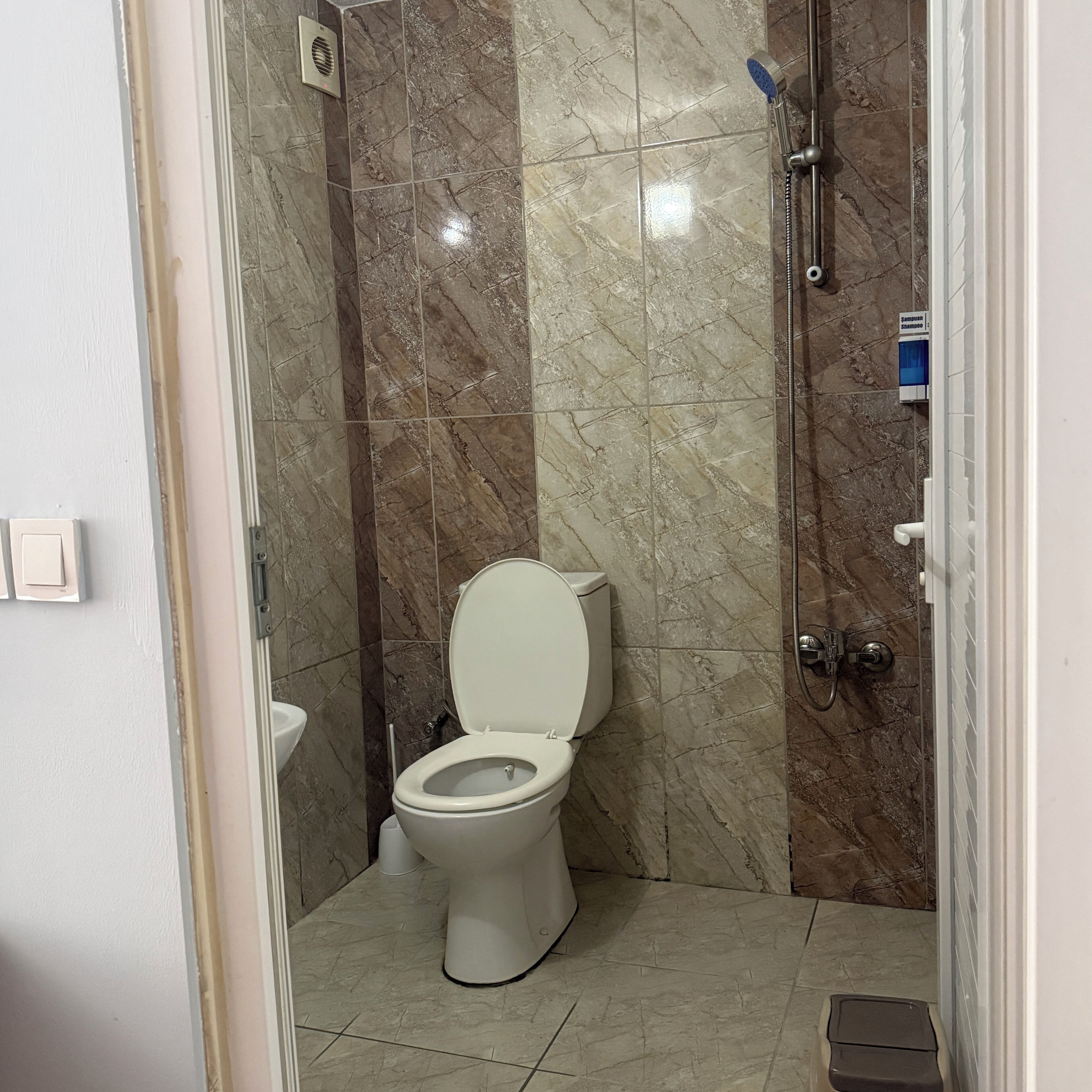 A bathroom with a toilet, a shower, and a sink.