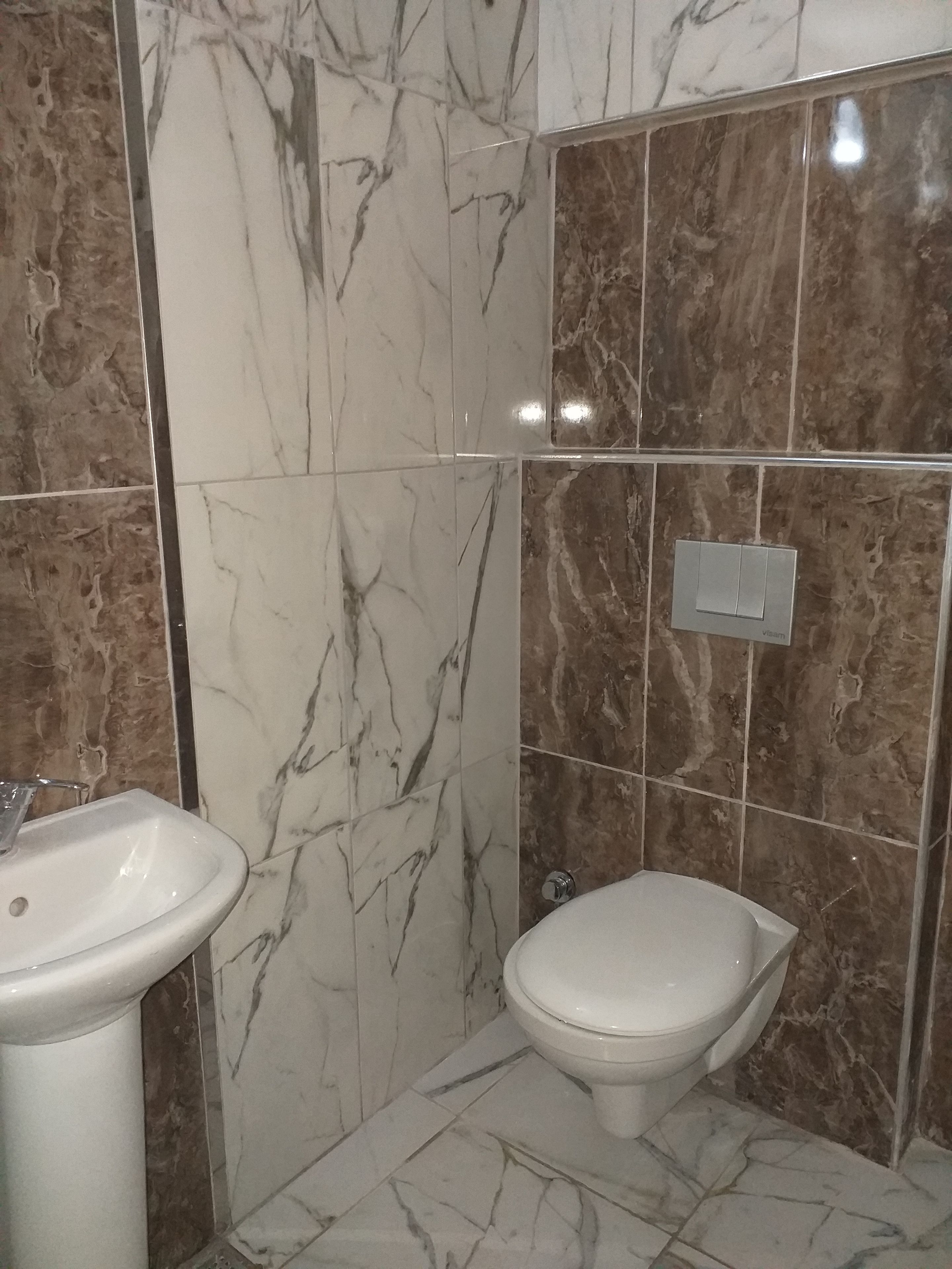 Un baño con lavamanos, inodoro y un interruptor de luz en la pared.
