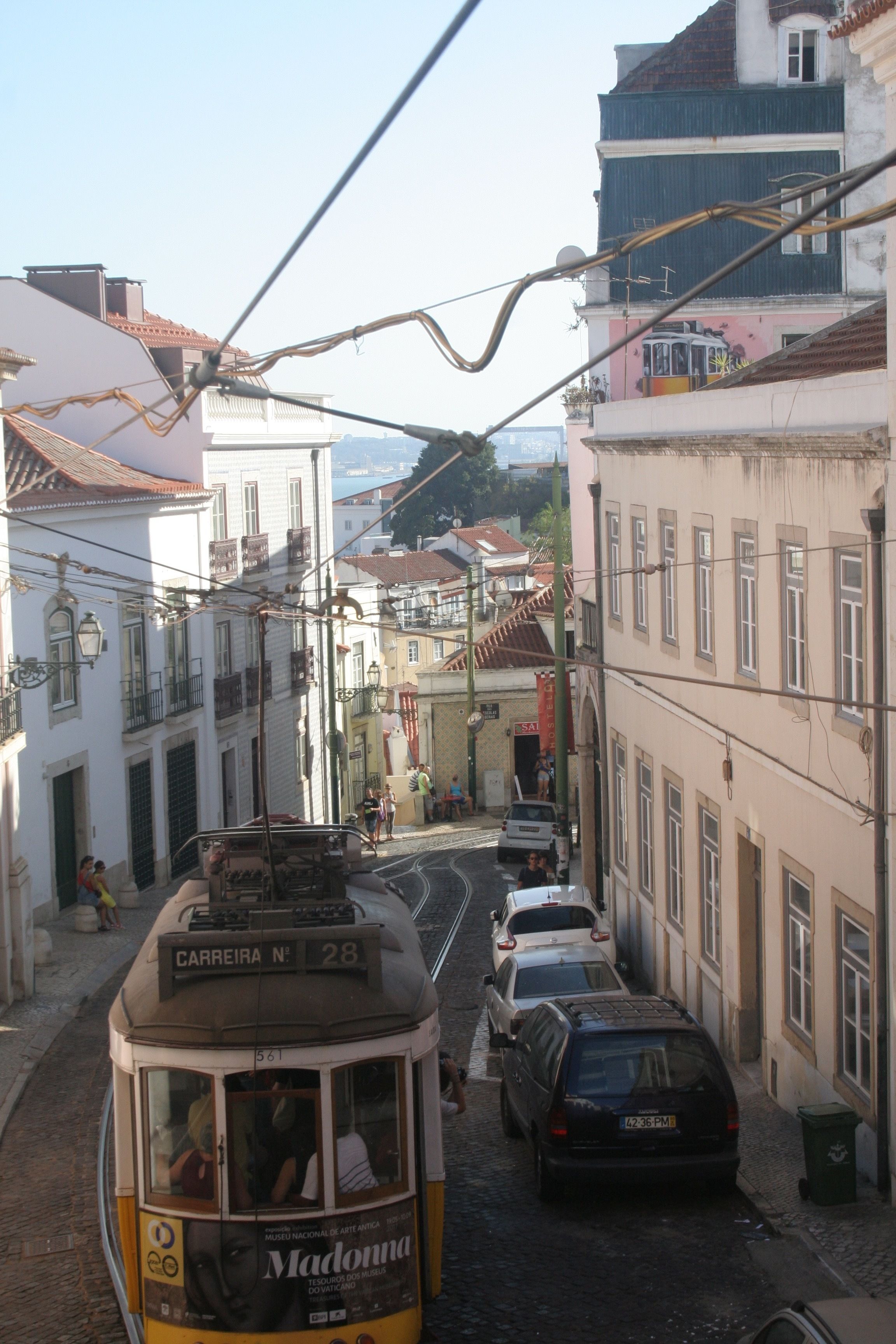 Un tramway circule dans une rue étroite, bordée de bâtiments des deux côtés.