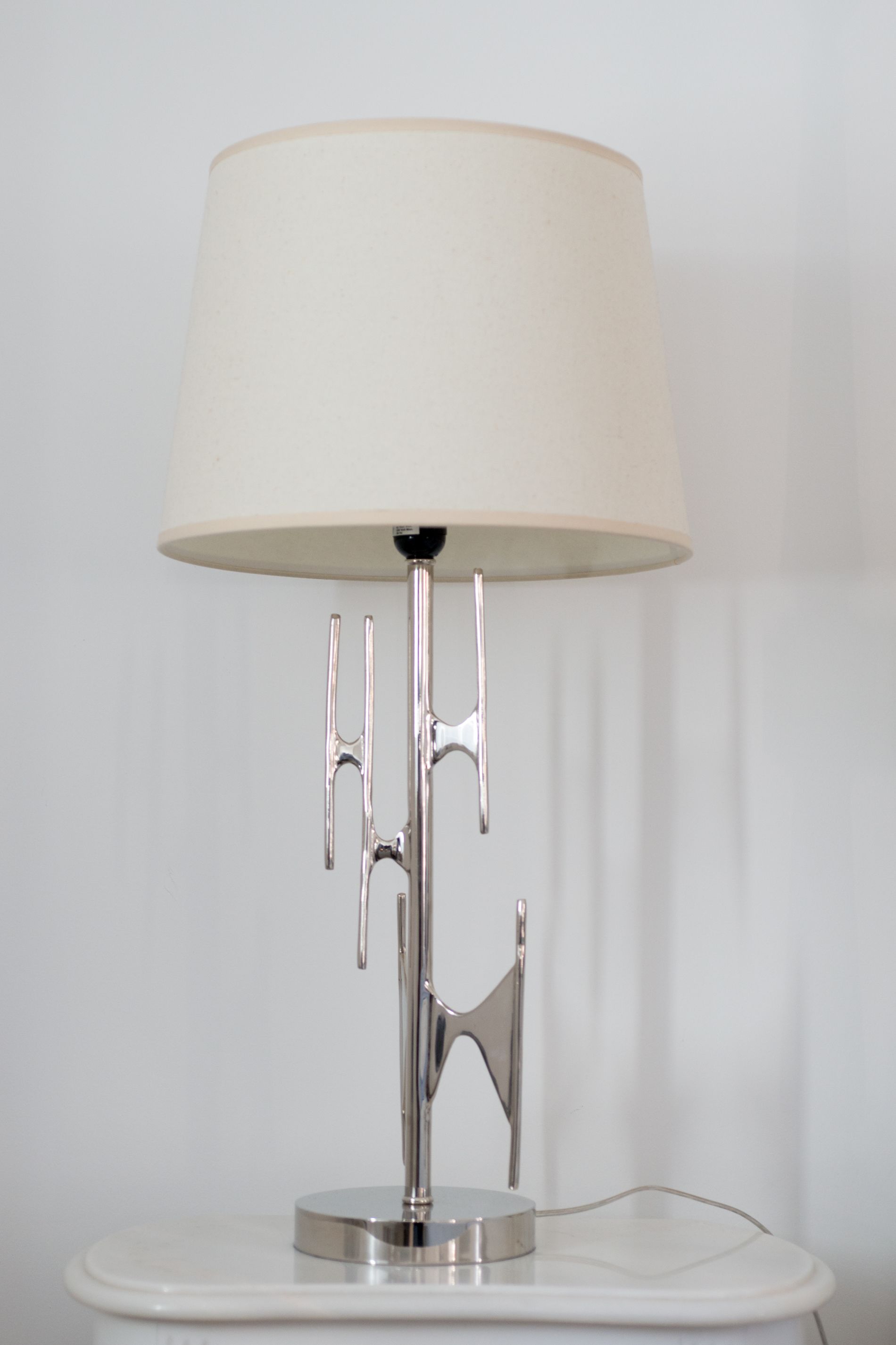A modern table lamp with a white shade and a metallic base.