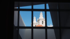 Une vue à travers une fenêtre à carreaux, qui révèle un bâtiment doté de deux dômes et d’un clocher.
