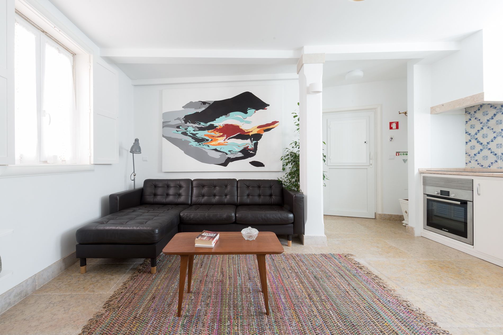 Ein modernes Wohnzimmer mit einem Ecksofa, einem Couchtisch und einem farbenfrohen, abstrakten Gemälde.