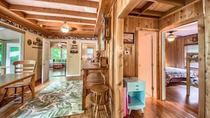 A wooden cabin interior with a dining area, a small kitchen, a bedroom with a bunk bed, and a bathroom. - Ponderosa Cabin (New Braunfels)